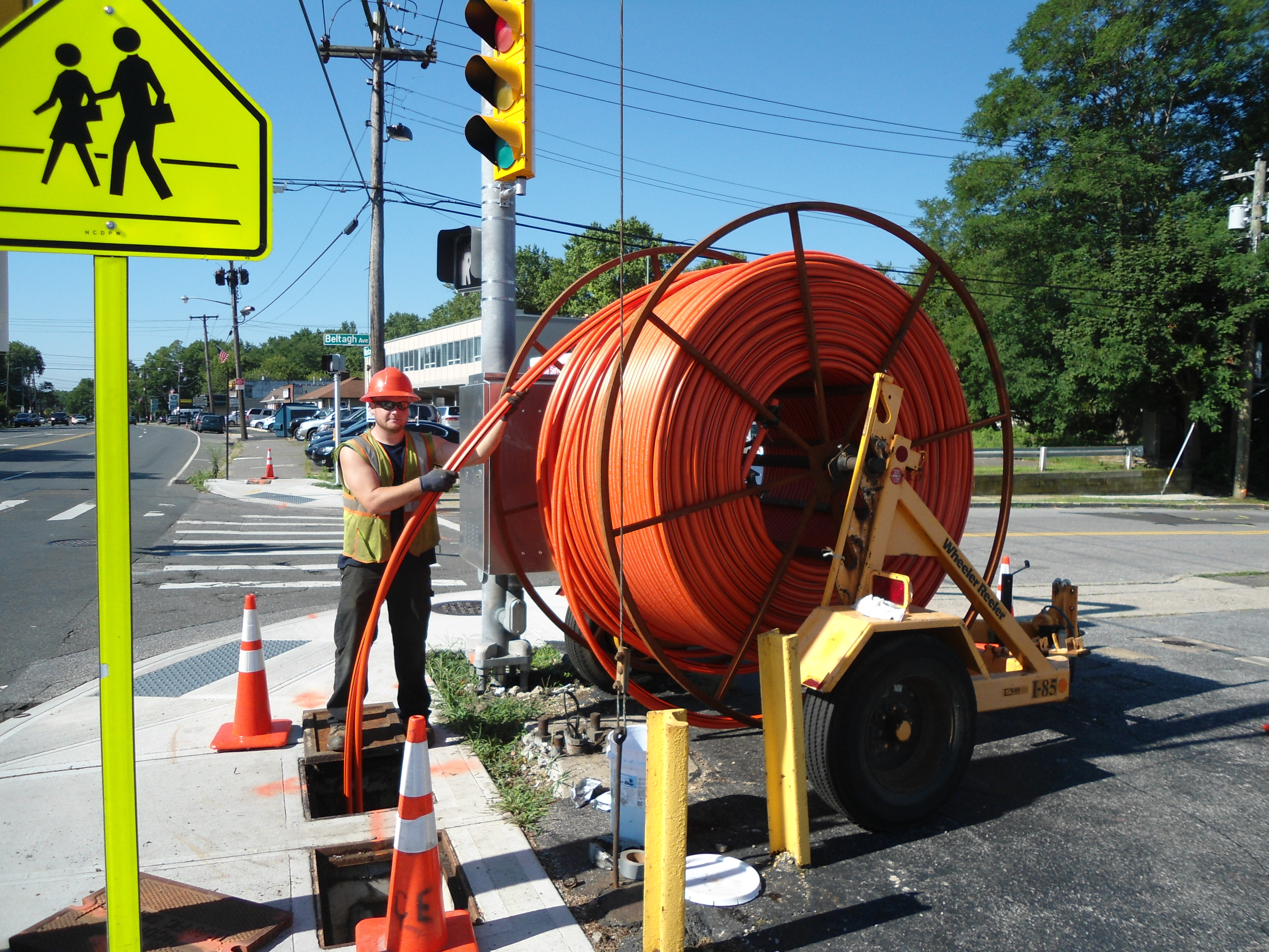 Employee working on the street with a giant spool of orange hose